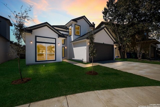 view of front facade with stucco siding, an attached garage, concrete driveway, and a front lawn