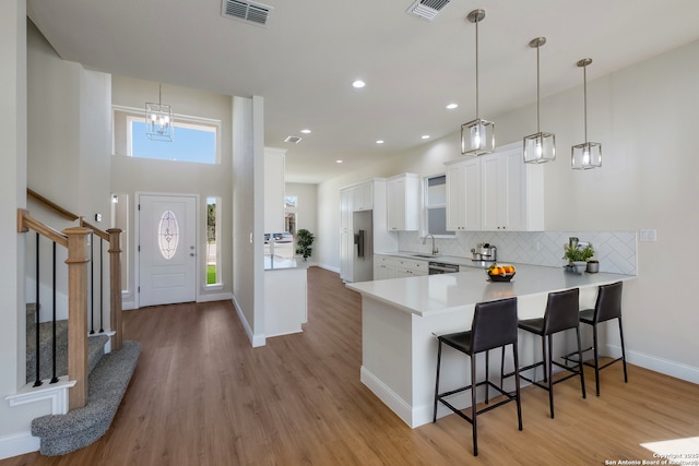 kitchen with decorative backsplash, a peninsula, visible vents, and a breakfast bar