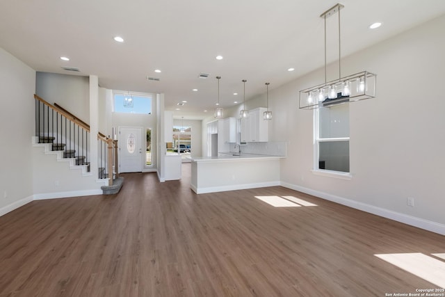 unfurnished living room with visible vents, dark wood-type flooring, baseboards, stairs, and recessed lighting