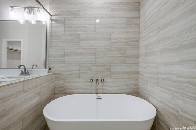 bathroom with vanity, a soaking tub, and tile walls