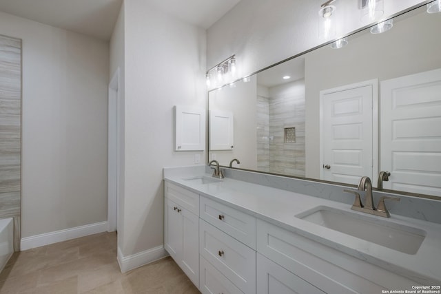 full bath featuring double vanity, tiled shower, baseboards, and a sink