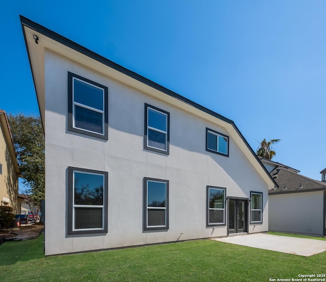 rear view of house with a patio, a yard, and stucco siding