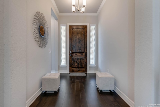 foyer featuring a notable chandelier, hardwood / wood-style floors, baseboards, and ornamental molding