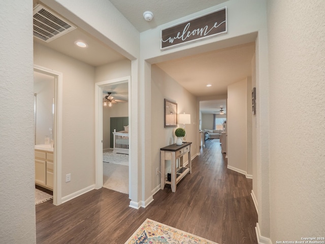 hallway featuring wood finished floors, visible vents, and baseboards