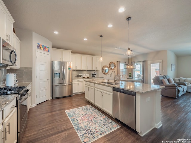 kitchen featuring dark wood-style floors, a sink, stainless steel appliances, white cabinets, and open floor plan