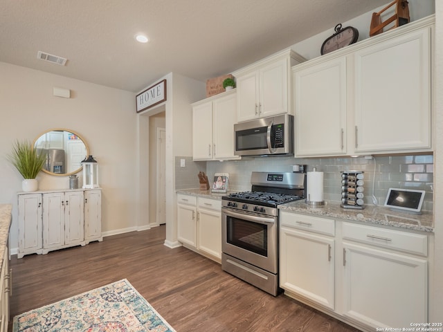 kitchen featuring visible vents, tasteful backsplash, dark wood-style floors, stainless steel appliances, and white cabinets