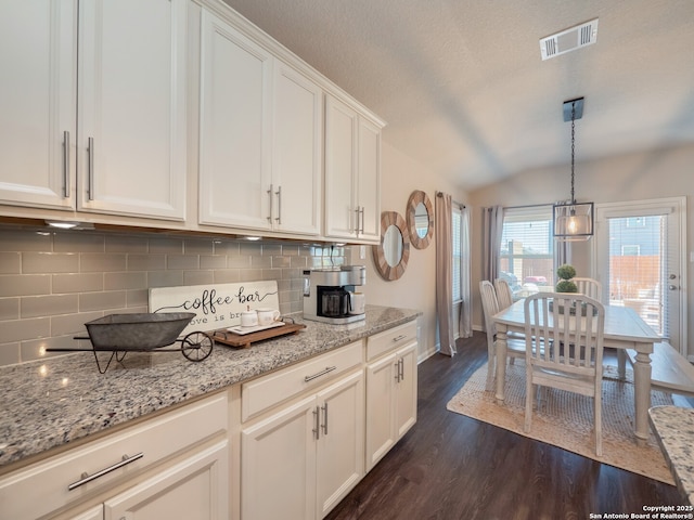 kitchen with visible vents, dark wood finished floors, vaulted ceiling, decorative backsplash, and white cabinetry