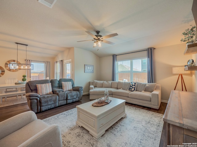 living room featuring visible vents, ceiling fan with notable chandelier, light wood-style flooring, and vaulted ceiling