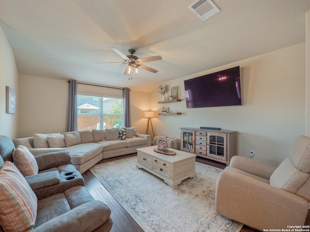 living area with visible vents, a textured ceiling, a ceiling fan, and light wood-style floors