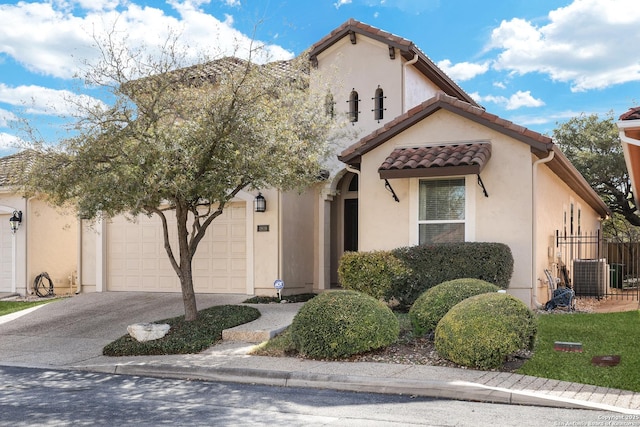 mediterranean / spanish-style home featuring a tiled roof, an attached garage, driveway, and stucco siding