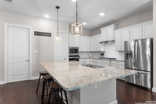 kitchen featuring a sink, decorative backsplash, dark wood-type flooring, under cabinet range hood, and appliances with stainless steel finishes