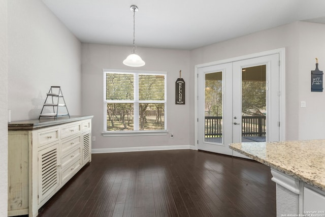 unfurnished dining area with baseboards and dark wood finished floors