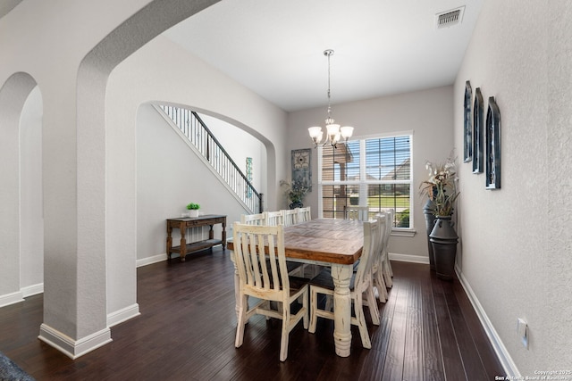 dining room with visible vents, dark wood-type flooring, arched walkways, baseboards, and a chandelier