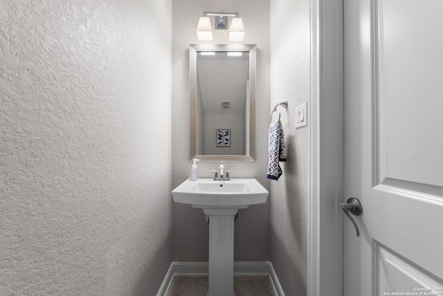 bathroom featuring a textured wall and baseboards