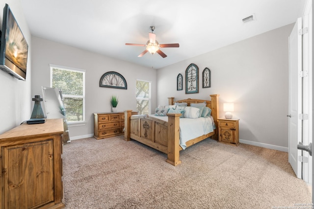 bedroom featuring visible vents, light colored carpet, baseboards, and ceiling fan