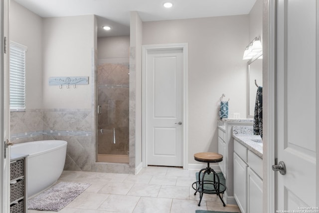 bathroom with a freestanding tub, tile walls, a shower stall, tile patterned flooring, and vanity