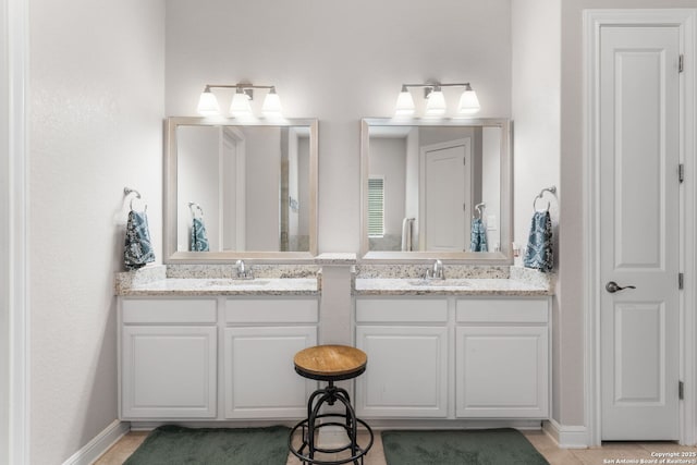 full bathroom with double vanity, baseboards, and a sink