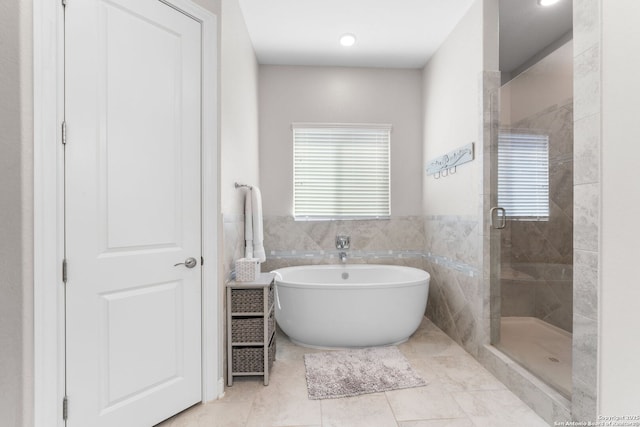 bathroom with a soaking tub, a shower stall, tile walls, and plenty of natural light