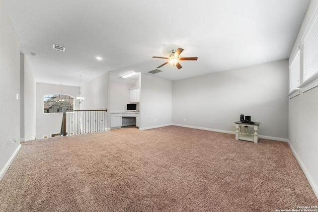 unfurnished living room with light carpet, visible vents, ceiling fan with notable chandelier, and baseboards