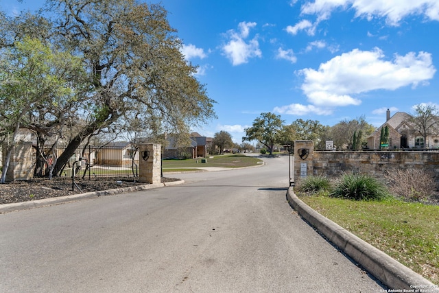 view of road with curbs, a residential view, and a gated entry