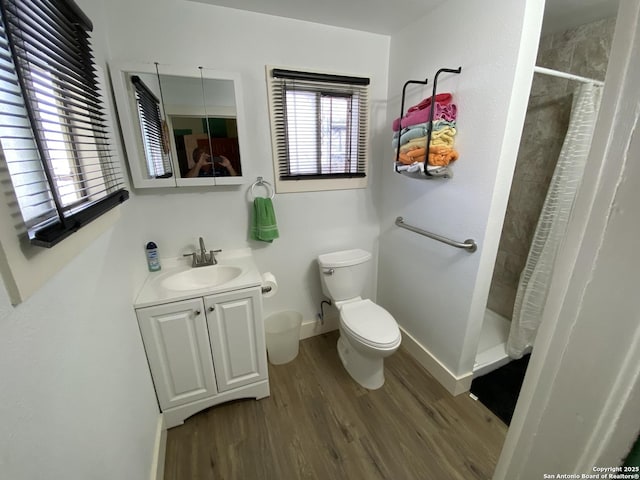 bathroom with toilet, a stall shower, wood finished floors, baseboards, and vanity