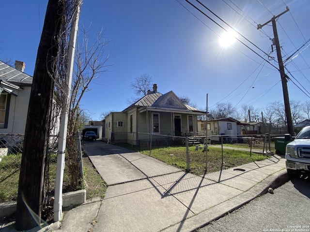 view of front of home featuring concrete driveway, a fenced front yard, and a chimney