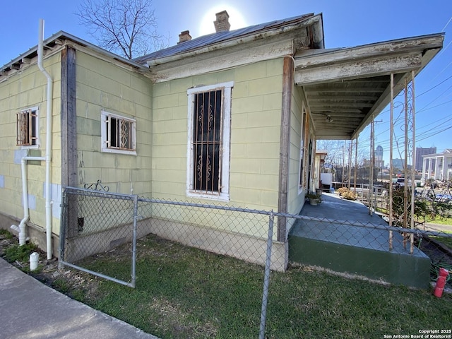 view of side of property featuring a carport, fence, and a chimney