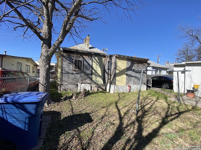 back of house featuring fence and a chimney