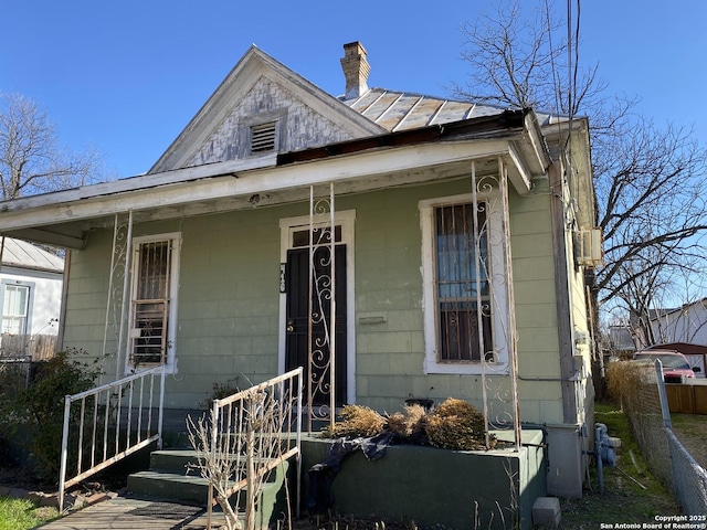 view of front facade with covered porch and a chimney