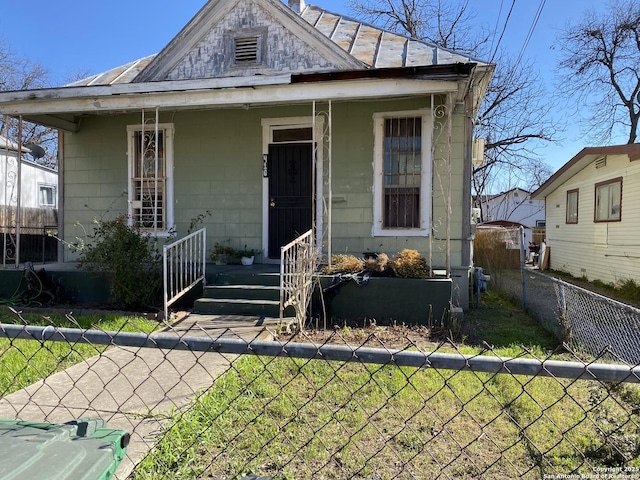 view of front facade featuring a porch, metal roof, a standing seam roof, and fence