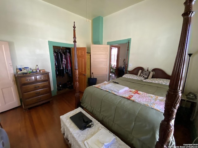 bedroom with wood finished floors, a closet, and a towering ceiling