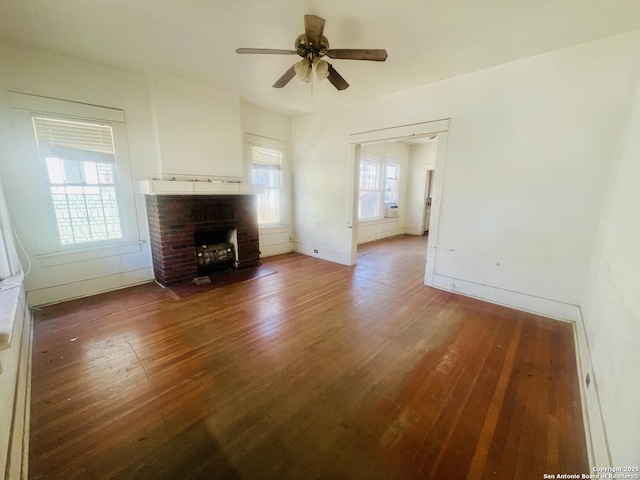 unfurnished living room featuring a brick fireplace, baseboards, ceiling fan, and hardwood / wood-style flooring