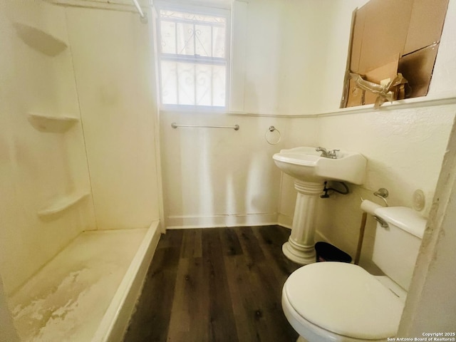 bathroom with baseboards, wood finished floors, toilet, and a stall shower