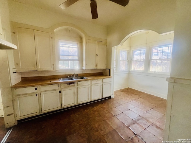 kitchen featuring decorative backsplash, a ceiling fan, baseboards, and a sink