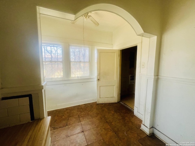 hall featuring arched walkways and wainscoting