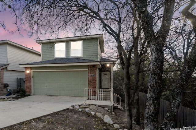 traditional-style home featuring a garage, brick siding, driveway, and fence