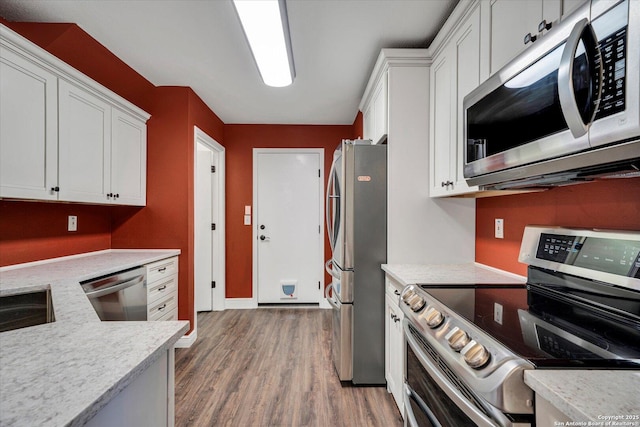 kitchen featuring light wood-style flooring, white cabinets, stainless steel appliances, and light countertops