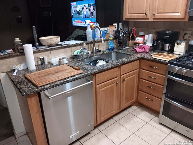 kitchen featuring decorative backsplash, dark stone counters, appliances with stainless steel finishes, and a sink