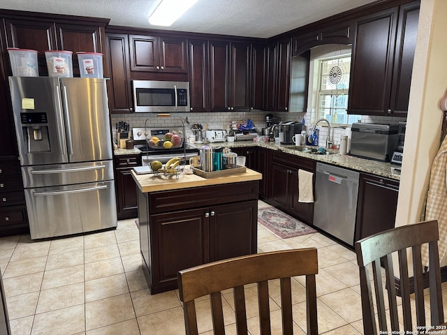 kitchen featuring a sink, stainless steel appliances, decorative backsplash, and light tile patterned floors