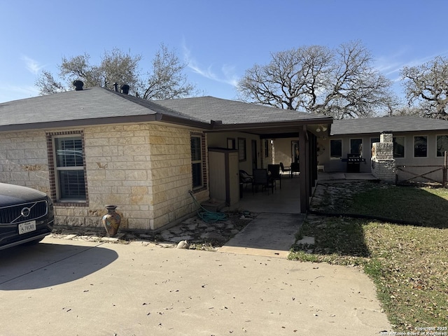 rear view of house featuring a patio and roof with shingles