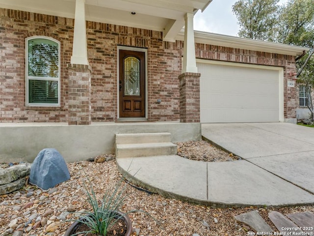 property entrance featuring brick siding, concrete driveway, and a garage