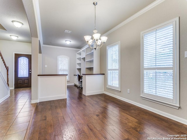 unfurnished dining area with a chandelier, crown molding, a wealth of natural light, and hardwood / wood-style floors