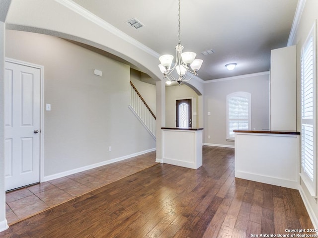 interior space with visible vents, crown molding, a chandelier, hardwood / wood-style flooring, and arched walkways