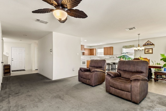 living area featuring visible vents, carpet flooring, and ceiling fan with notable chandelier