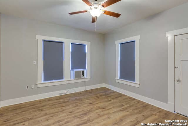 empty room with baseboards, wood finished floors, and a ceiling fan