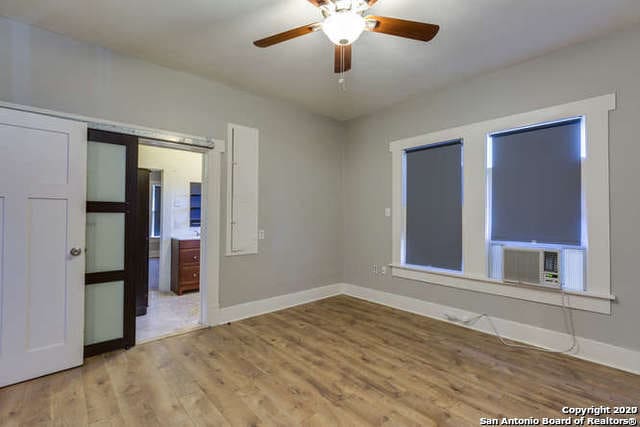 unfurnished room featuring cooling unit, baseboards, wood finished floors, and ceiling fan