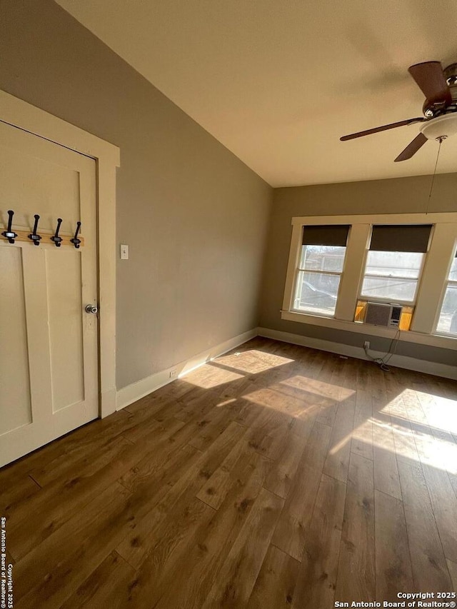 spare room featuring dark wood finished floors, lofted ceiling, baseboards, and ceiling fan