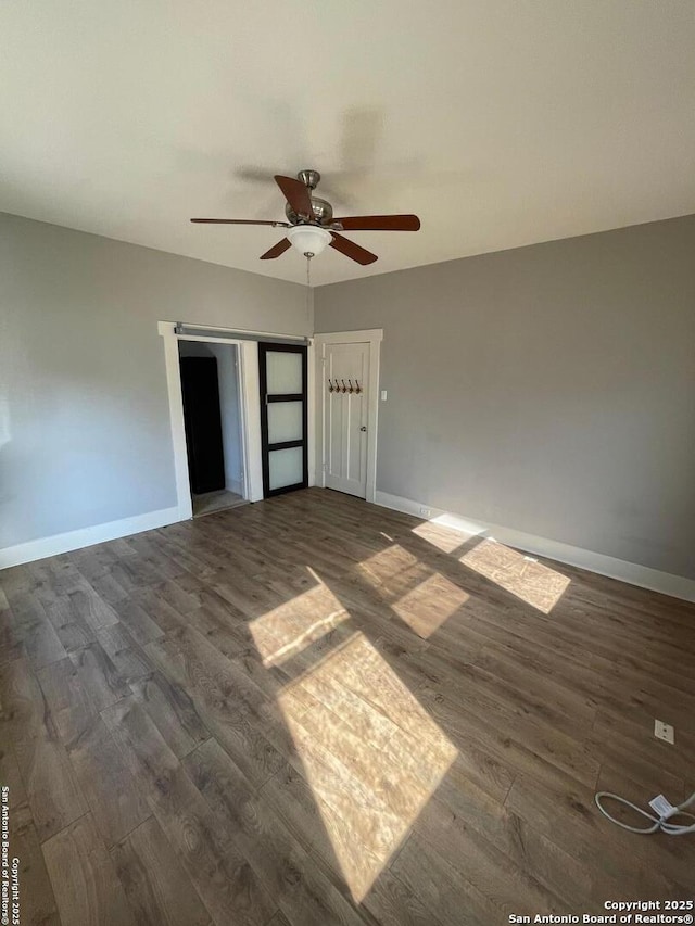 interior space featuring baseboards, dark wood-type flooring, and a ceiling fan