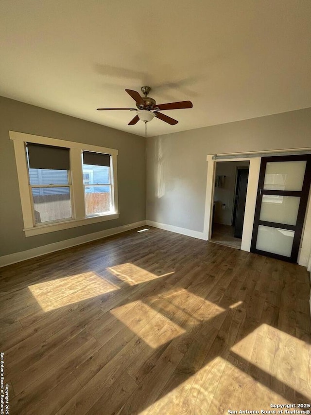 unfurnished bedroom with a ceiling fan, wood finished floors, and baseboards