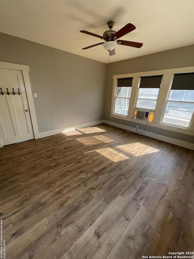 spare room with dark wood finished floors, baseboards, and ceiling fan